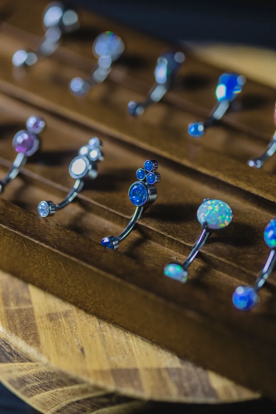 Blue opal and crystal belly rings on a wooden display